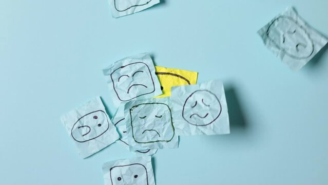 Sad faces on blue stickers and one yellow happy one. Positive sticker, smile sign on background of sad symbols. Concept of success and winning in business.