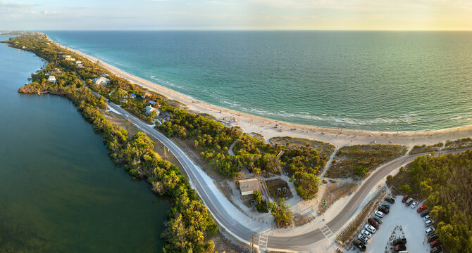 Parking lot for tourists cars in front of ocean beach with soft white sand in Florida. Popular vacation spot at sunset