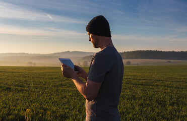 Man, traveler in hat using tablet in spring fog Czech landscape