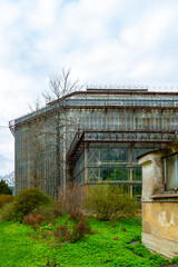 Aged urban greenhouse with large glass panels, set against a modern city tower, located within a...