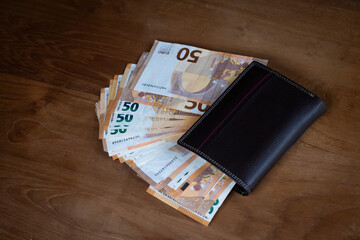 gros plan sur un portefeuille posé sur une table,  plein de billets de 50 euros