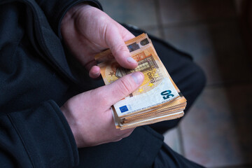 gros plan sur des mains qui tiennent une liasse de billets de 50 euros