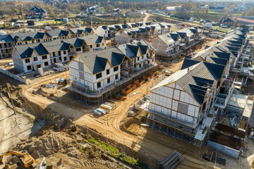 Fototapeta premium Aerial view building site with residential buildings under construction. New residential development with modern townhouses