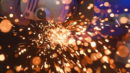 Craftsman working with grinder at industrial plant, man grinding iron detail, sparks flying around...