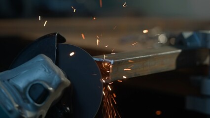 Craftsman working with grinder at industrial plant, man grinding edge of iron detail, sparks flying...