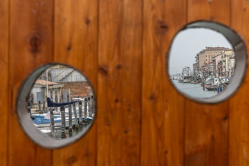 Chioggia cityscape in Venice Lagoon with narrow Vena water canal with colorful boats among old...