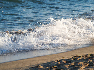 Photo on the surface of crashed waves on the beach of the coast. Tropical surf on the beach. waves on the golden sand of the beach. Fantastic sea view with calm sea water waves and sunlight
