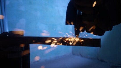 Craftsman working with grinder at industrial plant, man grinding iron detail, sparks flying around...