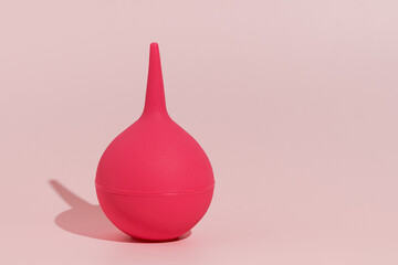Image of a pink rubber enema on a pink isolated background. Concept of medicine and pharmaceutical products, body detox. Place for your text and design