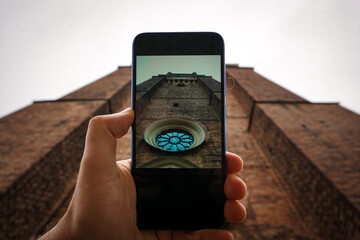 Cropped hand holding a phone photographing a tower
