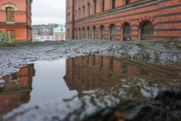 Close up of a puddle in front of buildings