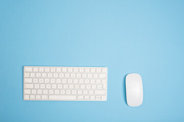 computer keyboard with a mouse on a blue background. Copy space