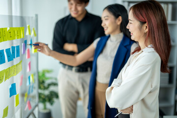 A group of people are working together on a whiteboard with colorful sticky notes. Scene is...