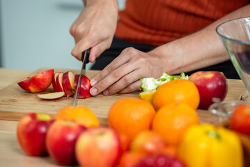 Hand chef knife cut and slice fresh Vegetables baby cos salad on wood board table .Make Salad Organic Vegetables mix lunch with green vegetables and fruit at kitchen table on wood cutting board.