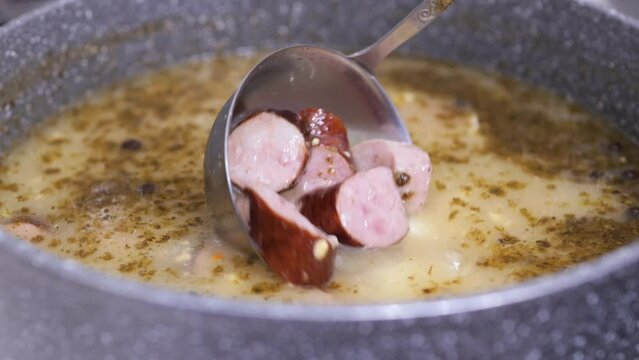 Traditional Polish zurek soup or white borscht in a pot. Tasty soup with sausages and eggs.