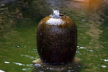 Ceramic fountain jar installed at the pond in the garden of the house. It is pottery for decorating...