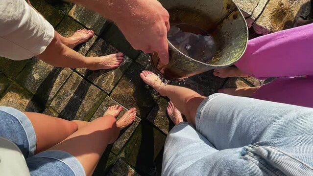 A group of tourists wash their nagas from a bucket. People wash their socks
