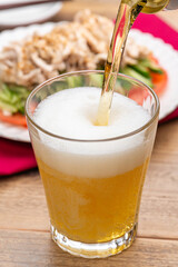 グラスに注がれるビールと棒棒鶏（バンバンジー）