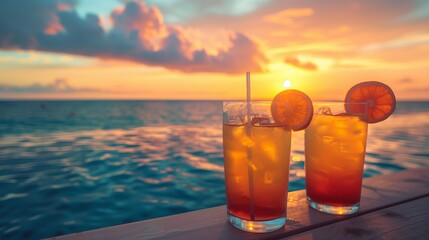 Two cocktails with straws on a dock at sunset by the ocean