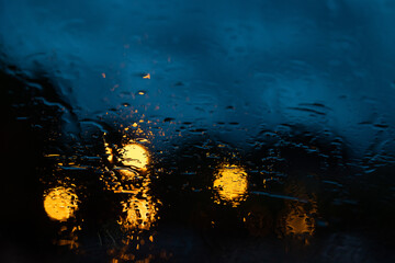 vista macro sulla superficie di vetro di un'auto bagnata dalla pioggia durante un temporale serale...