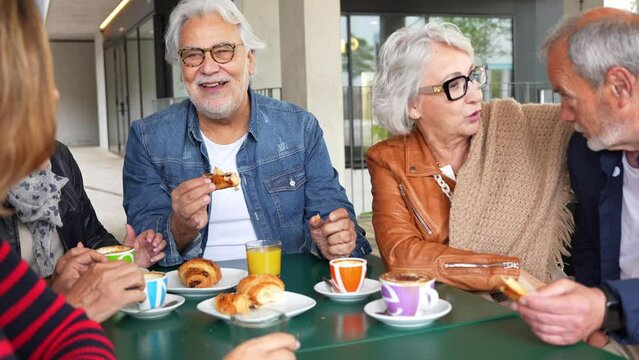 Happy senior people having breakfast sitting at cafe bar - Group of older friends having lunch at restaurant table - 4K slow motion video