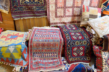 Variety of multi colored turkish carpets and prayer mats offered for sale on the market Grand Bazaar, Istanbul. Authentic gifts from travels by Turkey.