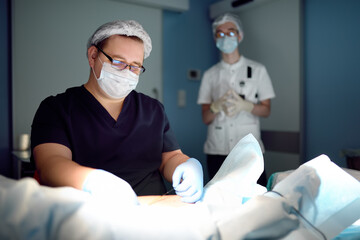 Professional vascular surgeon and assistant in the operating room of the clinic during vein...