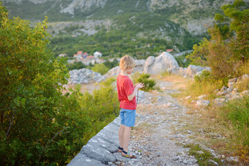 Preteen boy hiking in mountains near Fort Kosmach in Montenegro. Fortress is located near Budva. Old castle was built as defensive structure and observation post. Sights of Montenegro.