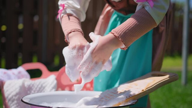 Close up footage of Washing clothes on old vintage washboard outdoors. Young Woman washing on old retro washboard 