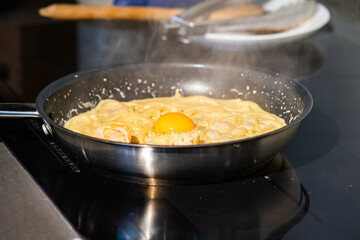 Close up macro to yolk in Creamy fried and boiled Spaghetti pasta in hot pan.