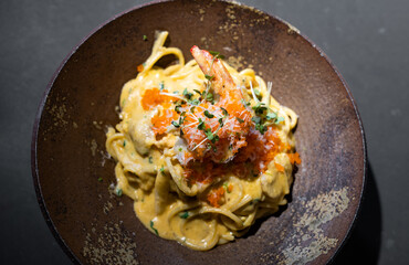 Spaghetti Carbonara pasta Egg and Cheese creamy cream sauce with Shrimp and micro herb decoration on the top of it of earthware circle bowl in studio light.