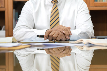 A senior lawyer in formal uniforms is in the middle of a meeting discussing matters in a meeting room with documents being placed on the table.