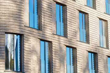 Row of floor to ceiling glass windows in modern building with clinker brick facade, showcasing the...