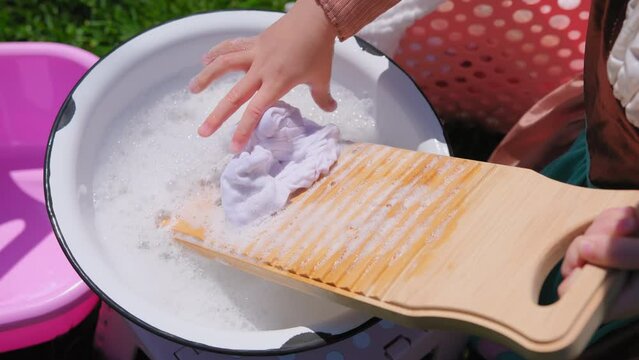 Washing clothes on old vintage washboard outdoors. Young Woman washing on old retro washboard. Close up shot 