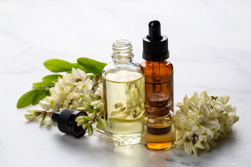 Robinia (false acacia) essential oil (remedy, extract) bottle with fresh acacia flowers
