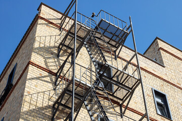 Fire escape hangs from brick buildings facade in city skyline