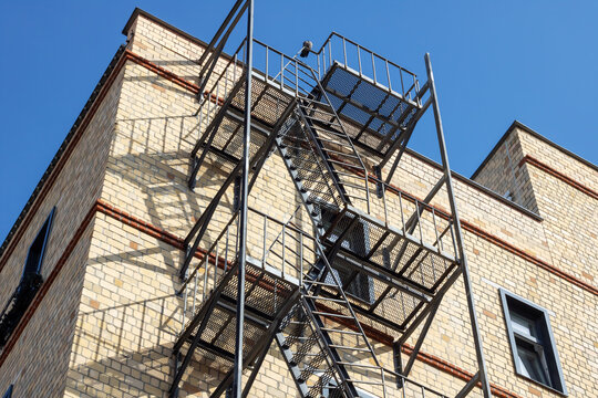 Fire escape hangs from brick buildings facade in city skyline