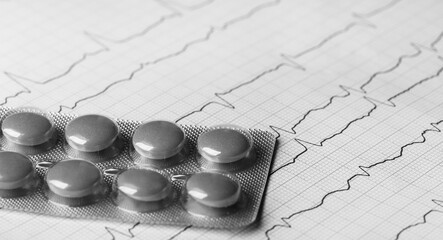 black and white medical pills on the background of a cardiogram