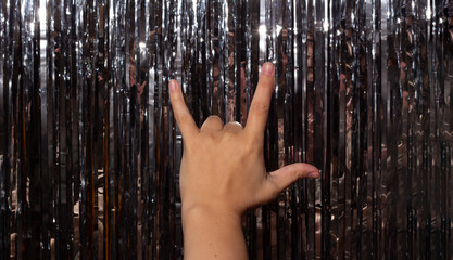 Female hand closeup shows rocker goat gesture. International gesture of love with fingers on shiny...