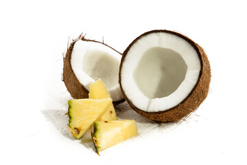 two halves of an opened coconut showing the white meat inside and pieces of pineapple isolated on...