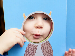 cute baby boy playing with card board cutouts of various animals