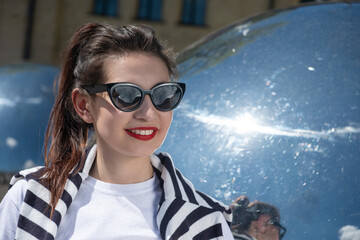 portrait of a young girl with red lips on a walk in the city in black glasses