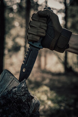 Hand of a hunter with a knife in the forest.