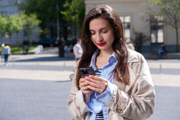 A brunette girl is looking at the phone, looking for a route in a new city. Tourism