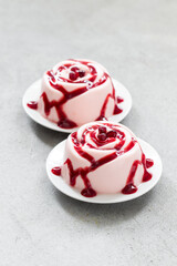 Vegan Pomegranate cream dessert, Panna Cotta in the shape of a rose. With pomegranate sauce. Light gray bacckground