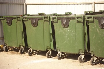 A row of dumpsters near a metal fence