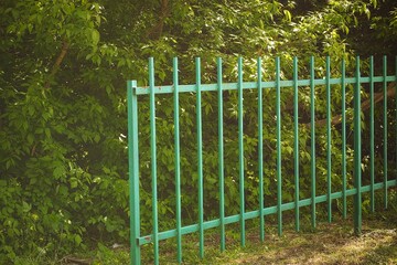 A green fence in front of foliage - Powered by Adobe