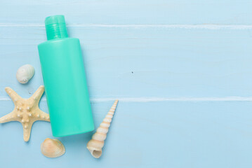 Sunscreen lotion with summer decor on wooden background, top view