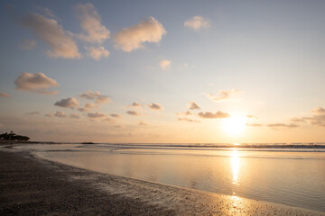 Fantastic sunset on the dream beach of Kuta, small waves setting over the sea and the reflection of...