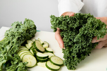 a chef holds a bunch of kale leaves to be cut up to make  a kale and cucumber salad